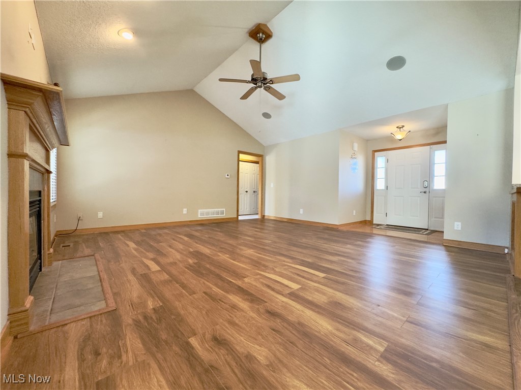 6014 Wentworth Road Southwest Canton, OH 44706 - Photo 3 of 22 Unfurnished living room with LVT floors, a gas fireplace, high vaulted ceiling, and ceiling fan