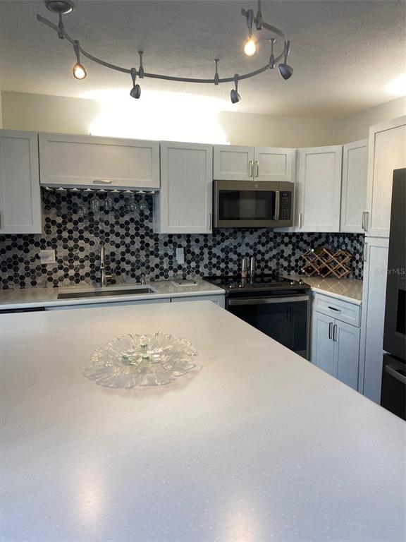 2209 Belleair Road, Unit C21 Clearwater, FL 33764 - Photo 11 of 23 a kitchen with stainless steel appliances kitchen island granite countertop a stove a sink and a refrigerator