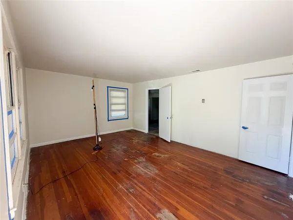 a view of an empty room with window and wooden floor