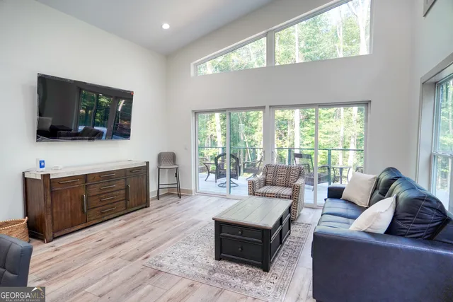 a living room with furniture a flat screen tv and a floor to ceiling window