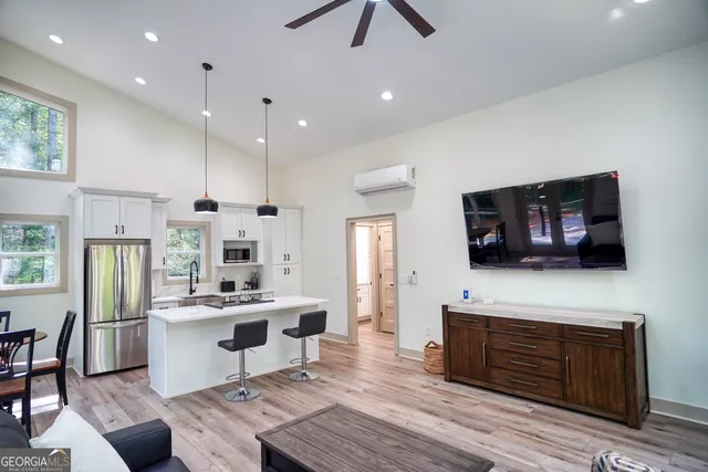 a living room with stainless steel appliances furniture a fireplace a flat screen tv and a kitchen view