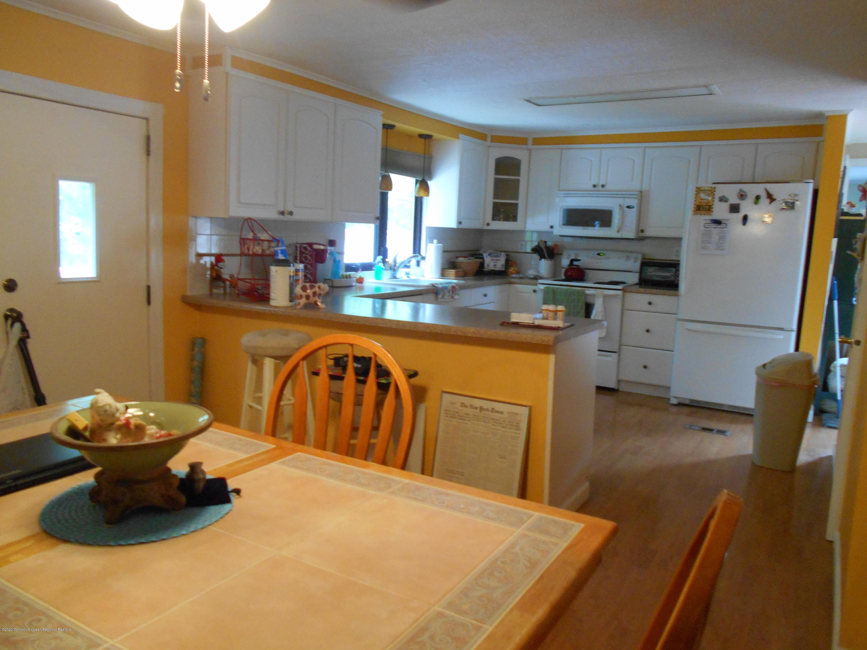 484 Rosalind Road Freehold, NJ 07728 - Photo 4 of 27 a kitchen with stainless steel appliances white cabinets sink and wooden floor