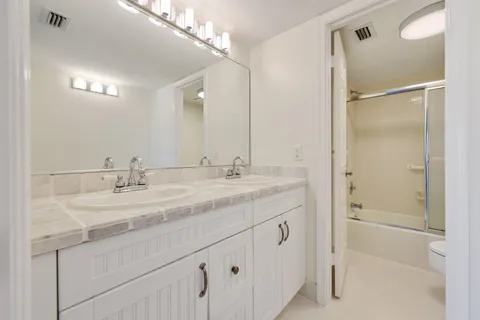 a bathroom with a granite countertop sink a mirror and a shower