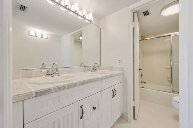 a bathroom with a granite countertop sink a mirror and a shower