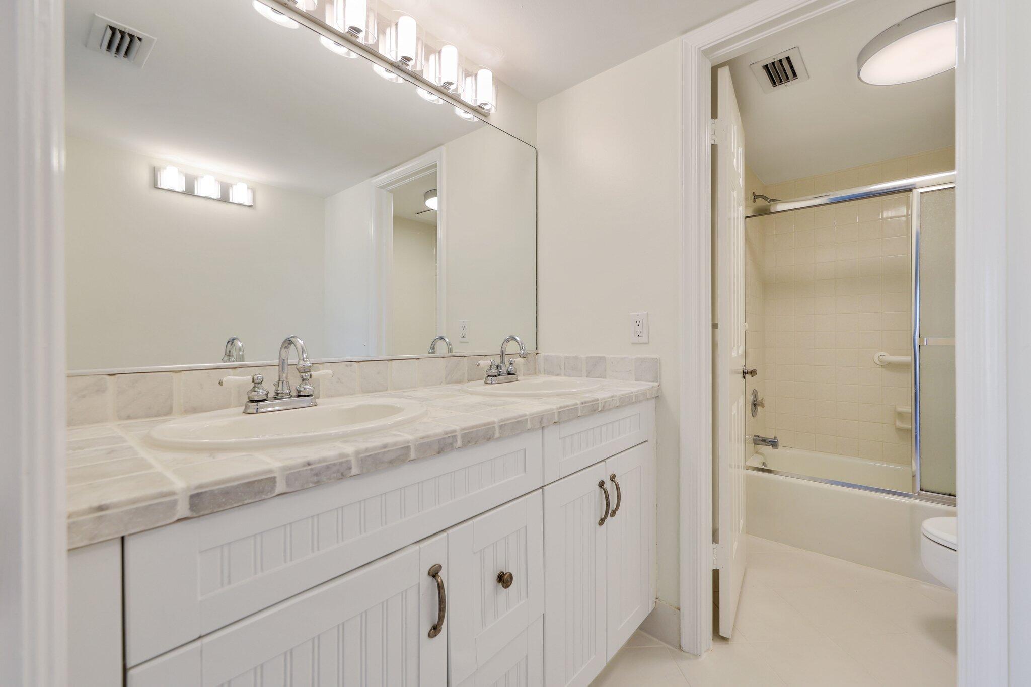 200 Intracoastal Place, Unit 206 Jupiter, FL 33469 - Photo 13 of 35 a bathroom with a granite countertop sink a mirror and a shower