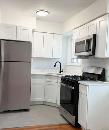 a kitchen with stainless steel appliances granite countertop white cabinets a refrigerator a sink a stove a microwave and white cabinets