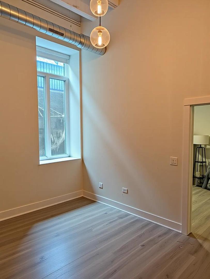 1453 Maple Avenue, Unit B06 Evanston, IL 60201 - Photo 4 of 16 an empty room with wooden floor fan and windows