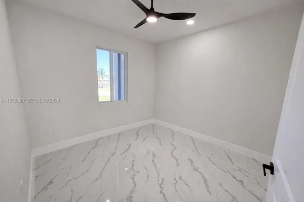 an empty room with windows and fan