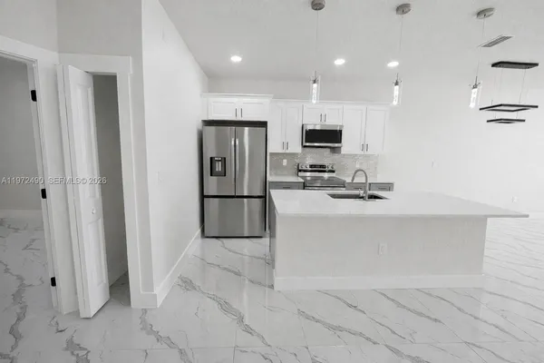 a kitchen with stainless steel appliances kitchen island granite countertop a refrigerator and a sink
