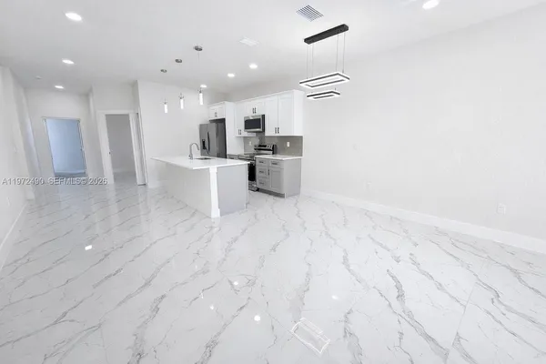 a view of kitchen with kitchen island stainless steel appliances refrigerator sink and cabinets