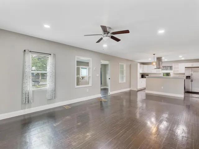 a view of an empty room with wooden floor and a ceiling fan