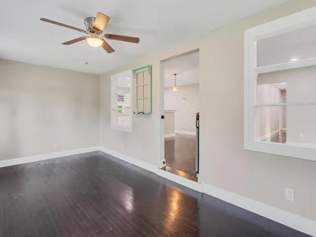 a view of a hallway with wooden floor and chandelier fan