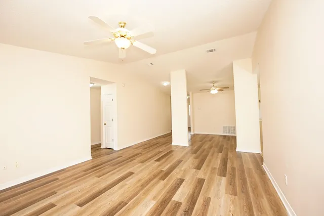 a view of an empty room and chandelier fan