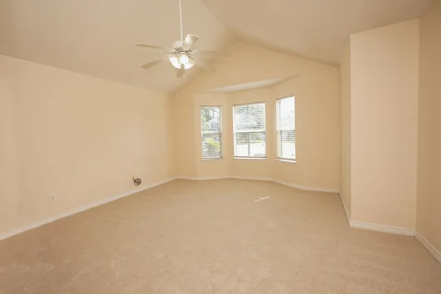 an empty room with windows and chandelier fan