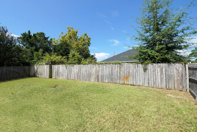 a view of a backyard with large trees and wooden fence