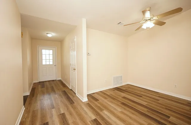 a view of a room with wooden floor and a ceiling fan