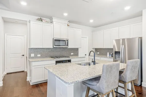 a kitchen with stainless steel appliances granite countertop a kitchen island a stove a table and a refrigerator