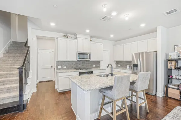 a kitchen with refrigerator a stove and chairs