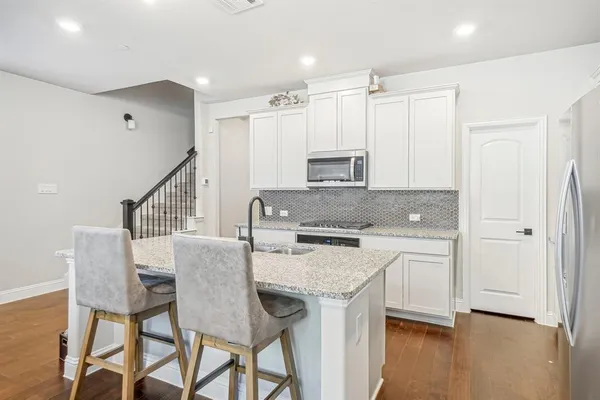 a kitchen with stainless steel appliances granite countertop a kitchen island hardwood floor and a sink