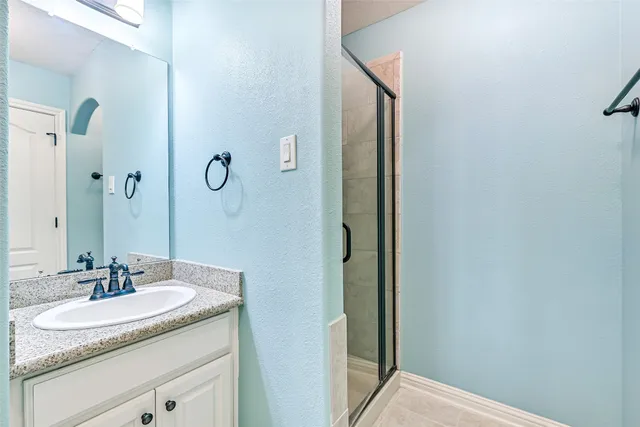 a view of a white house in front of a big yard with plants and large trees