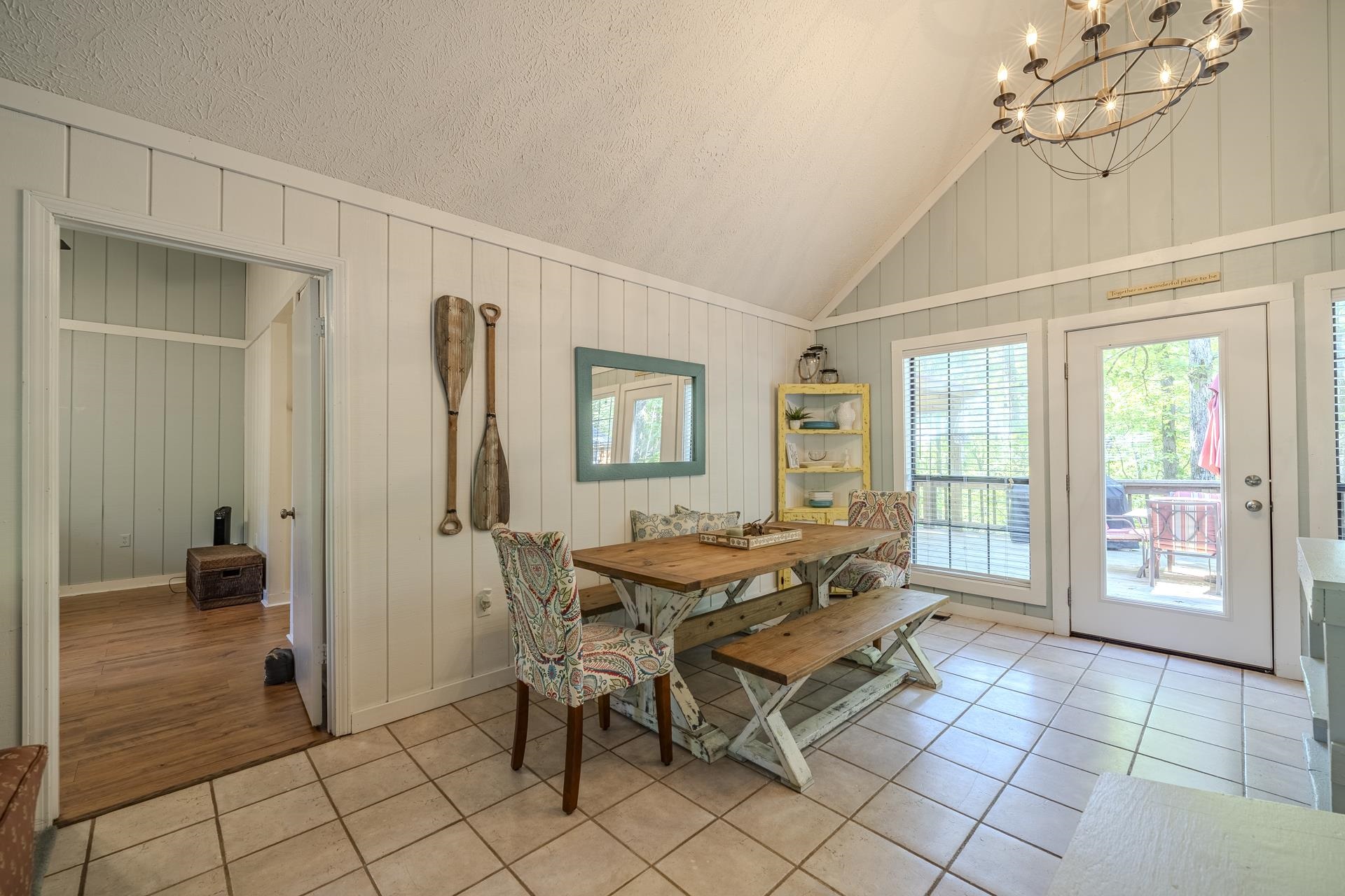 80 Contreau Road Counce, TN 38326 - Photo 11 of 28 Dining area featuring a vaulted ceiling with a large chandelier, tile flooring, and light-colored vertical wall paneling