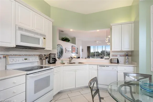 a kitchen with a sink white cabinets and appliances
