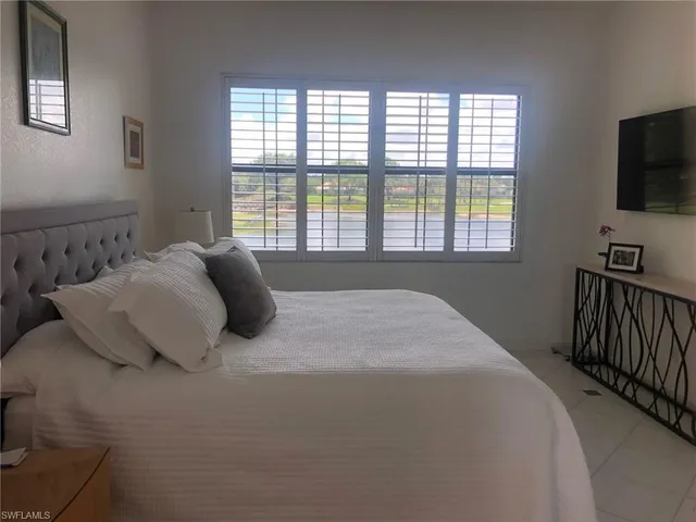 a bedroom with a bed and a flat tv screen on a dresser
