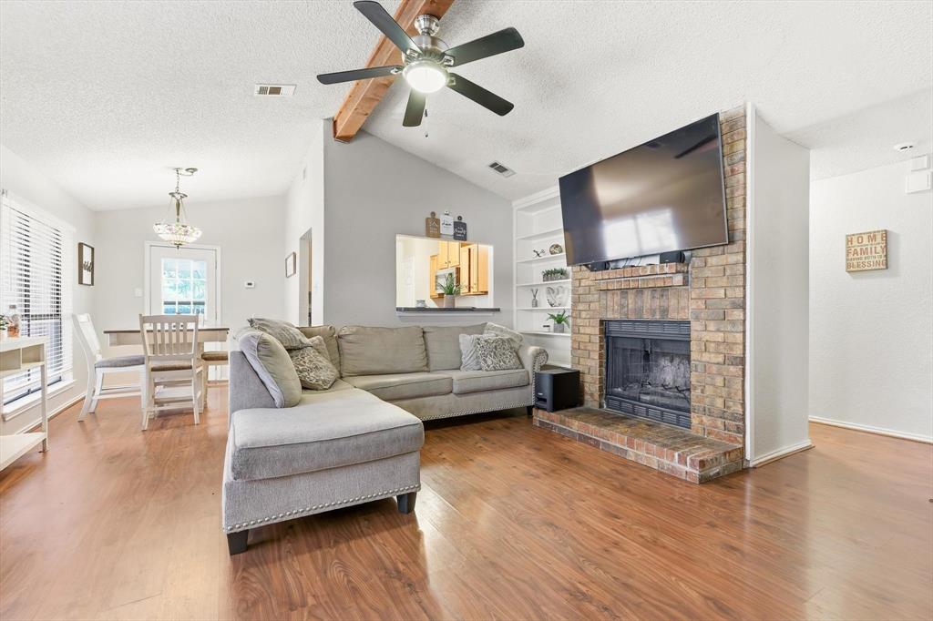 1312 Hackamore Street Mesquite, TX 75149 - Photo 2 of 23 Living area featuring beam ceiling, a textured ceiling, built in features, ceiling fan, and a fireplace