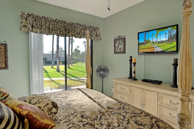 a bedroom with a bed and a flat tv screen on dresser