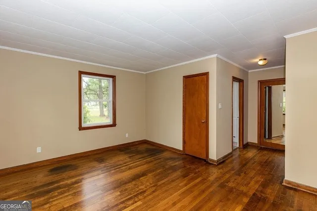 a view of an empty room with wooden floor and a window