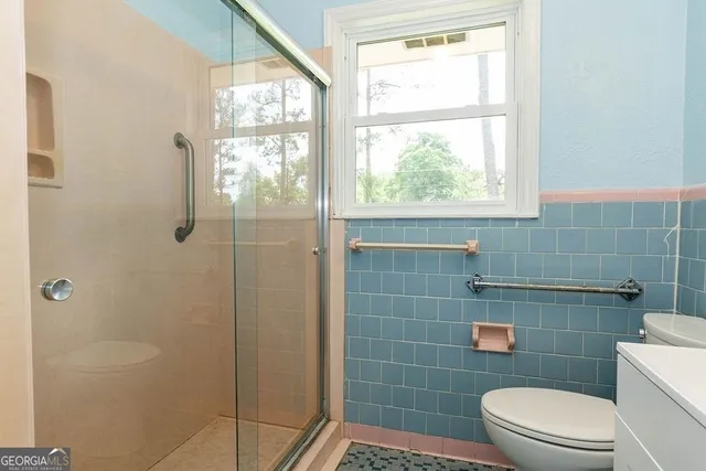 a bathroom with a toilet a window and shower