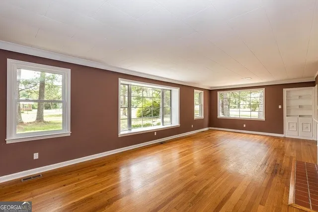 a view of an empty room with wooden floor and a window