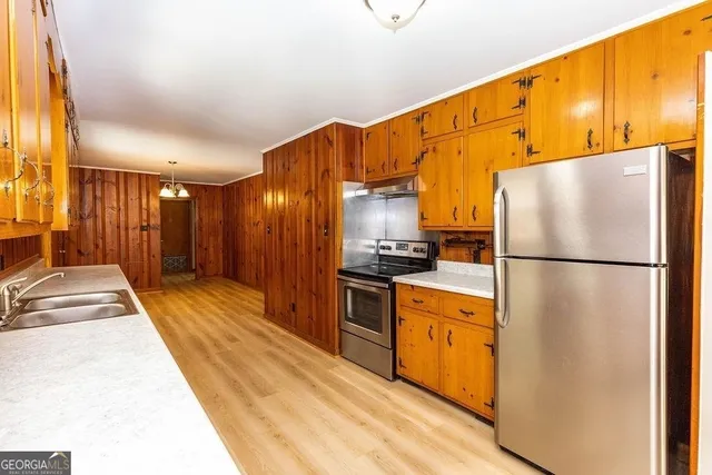 a kitchen with stainless steel appliances granite countertop a refrigerator a stove and a sink with wooden floor
