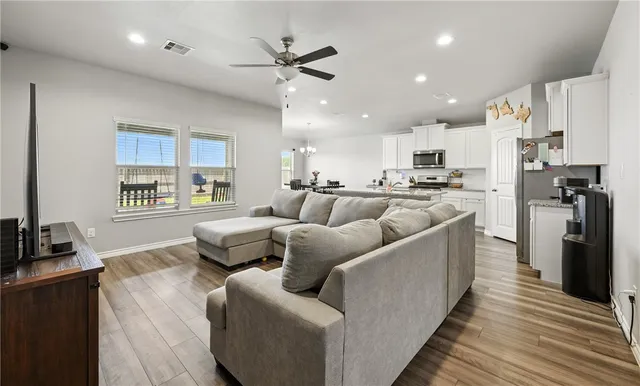 a living room with stainless steel appliances furniture and a kitchen view