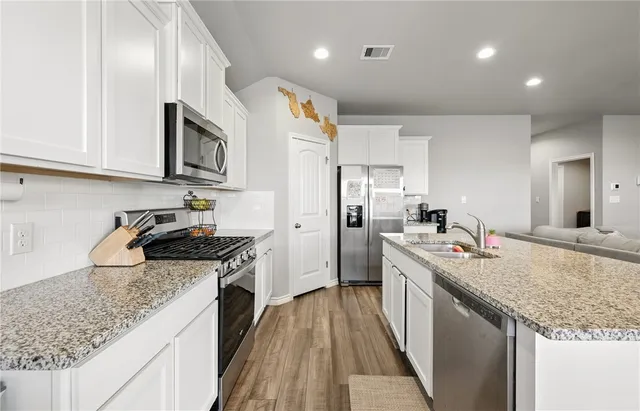 a kitchen with stainless steel appliances granite countertop a sink stove and refrigerator