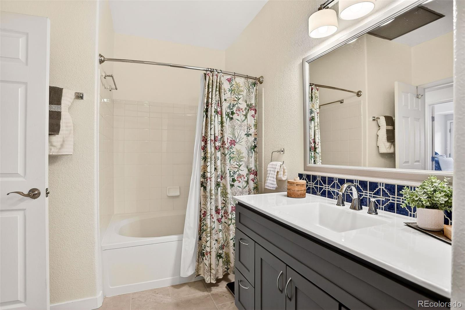 10715 Twenty Mile Road, Unit 202 Parker, CO 80134 - Photo 21 of 26 a bathroom with a granite countertop sink a mirror a shower and a bathtub