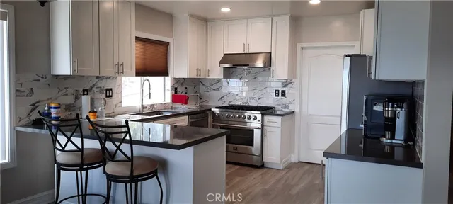 a kitchen with stainless steel appliances granite countertop a stove refrigerator sink and cabinets