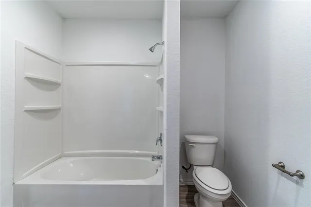 a white toilet sitting next to a bath tub