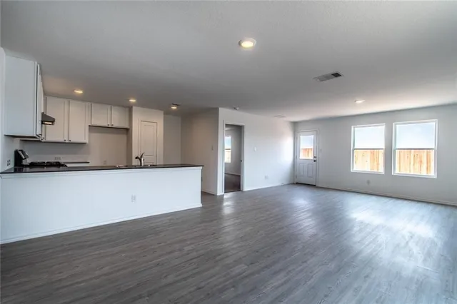 a view of an empty room with window and wooden floor