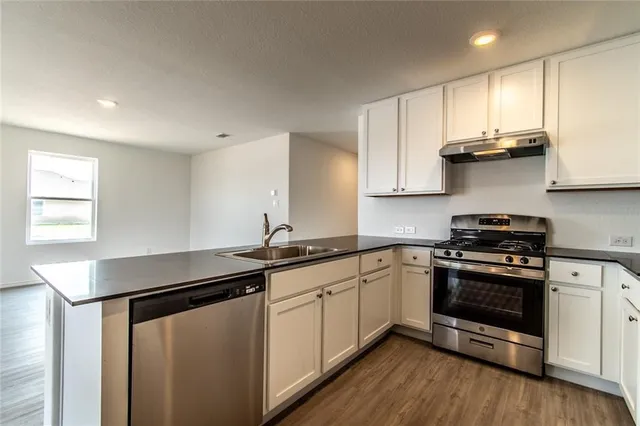 a kitchen with stainless steel appliances a sink cabinets and wooden floor