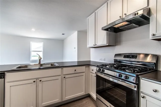 a kitchen with stainless steel appliances granite countertop white cabinets and a stove a sink