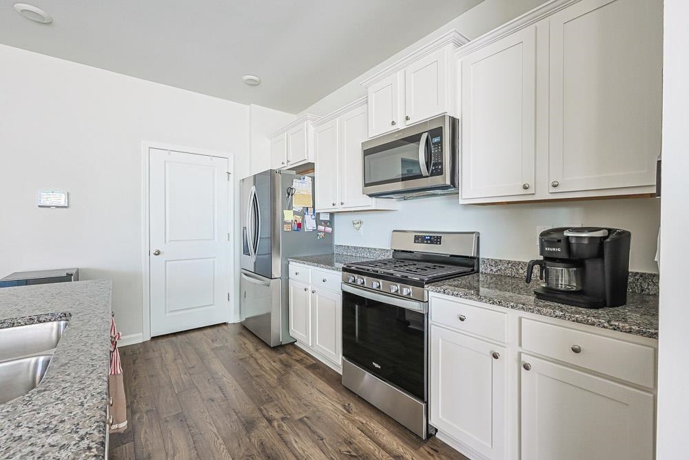 2115 Ridgedale Drive Conway, SC 29526 - Photo 7 of 38 Kitchen featuring appliances with stainless steel finishes, white cabinets, dark wood-type flooring, and dark stone counters