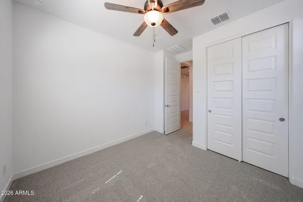 an empty room with closet and a chandelier fan
