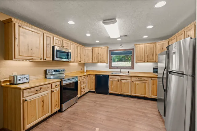 a kitchen with granite countertop a refrigerator stove top oven and sink