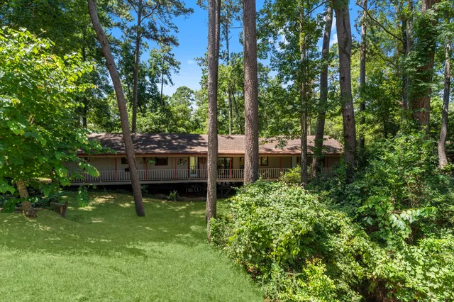 a backyard of a house with table and chairs large trees