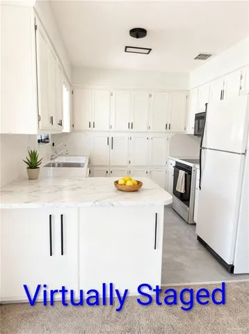 a kitchen with kitchen island a sink a refrigerator and a stove