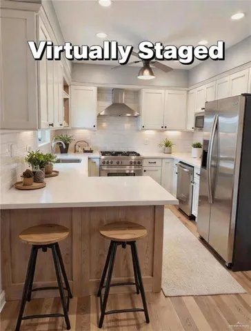 a kitchen with stainless steel appliances a sink a stove and white cabinets