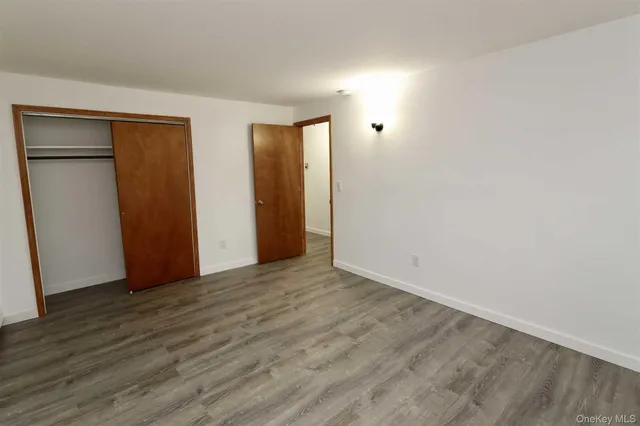 a view of an empty room with wooden floor and closet