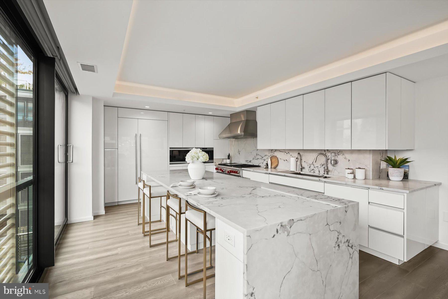 925 H Street Northwest, Unit 901/902 Washington, DC 20001 - Photo 10 of 29 a kitchen with a stove a refrigerator white cabinets and wooden floor