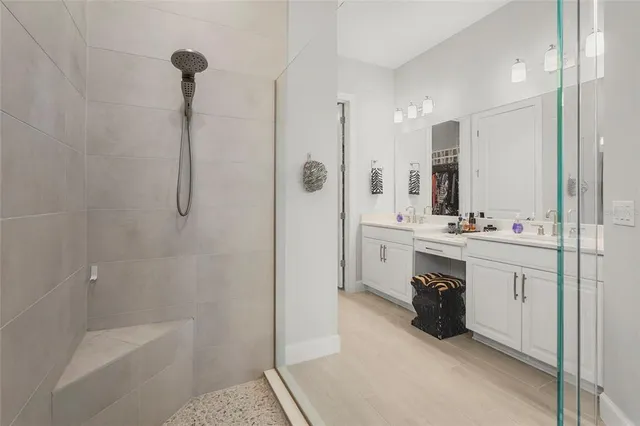 a bathroom with a double vanity sink a mirror a bathtub and shower